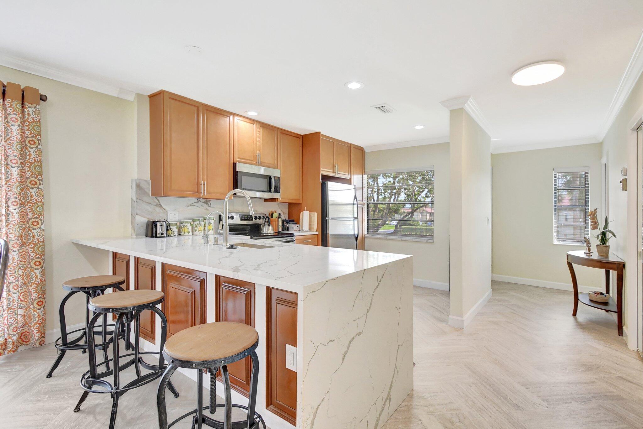 21209 Lago Circle, Unit 12G Boca Raton, FL 33433 - Photo 11 of 39 a kitchen with granite countertop a table chairs stove a sink and dishwasher