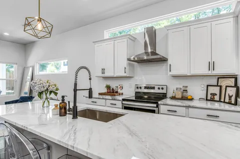 a kitchen with stainless steel appliances granite countertop a stove a sink and a white cabinets