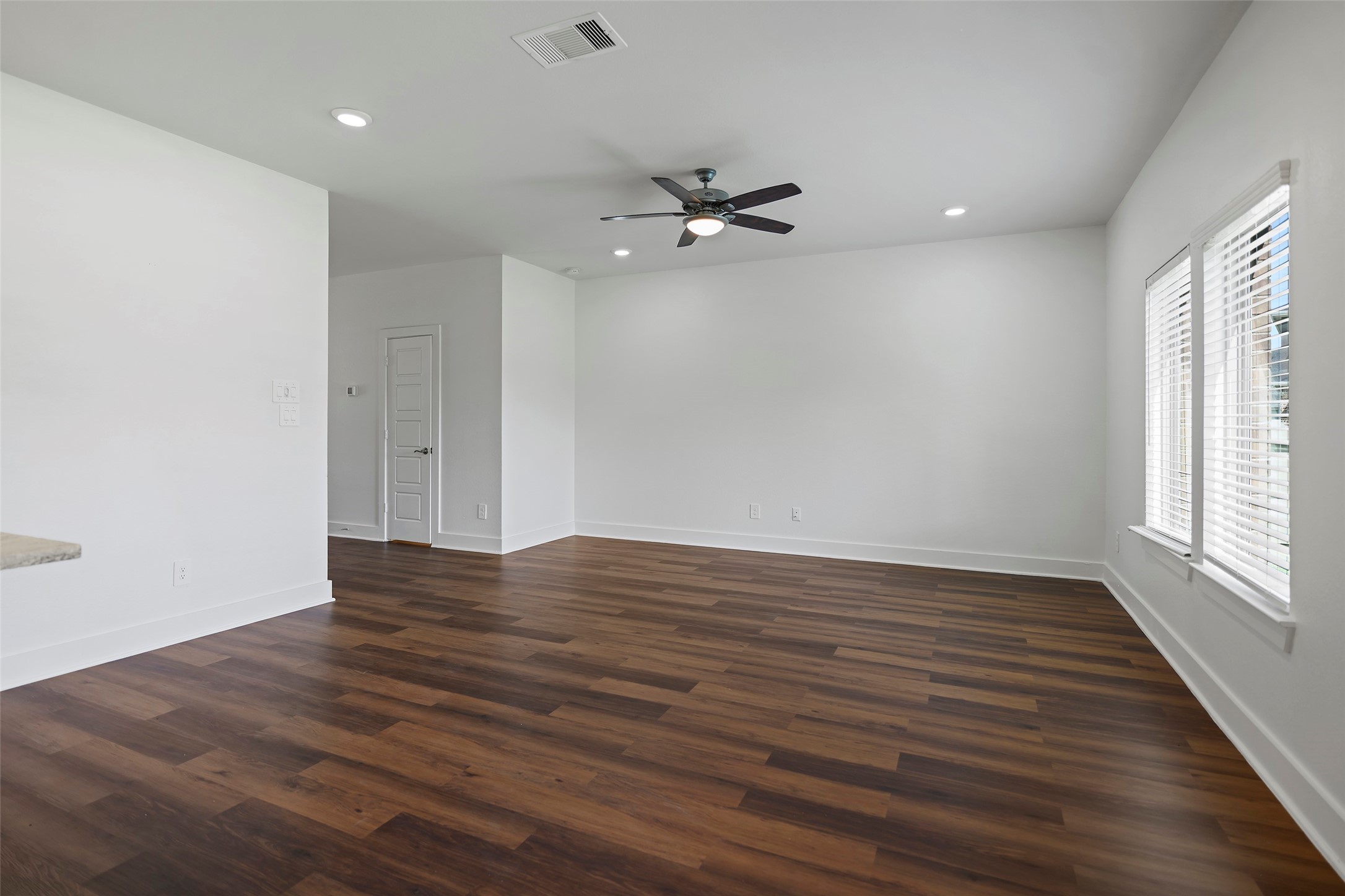10603 Whitejacket Conroe, TX 77385 - Photo 21 of 42 The living room features a spacious open layout with wood flooring, a ceiling fan, and ample natural light from large windows. Perfect for a living or dining area, it offers a modern and inviting atmosphere.