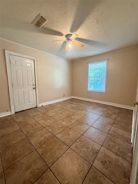 217 3rd St Pinehill Springhill, LA 71075 - Photo 7 of 23 Spacious room featuring neutral-toned tile flooring, a ceiling fan with integrated lighting, a single window, and a paneled interior door