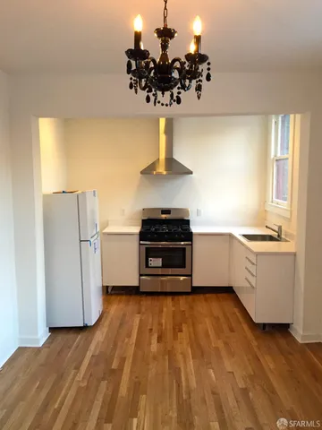 a kitchen with wooden floors and white stainless steel appliances