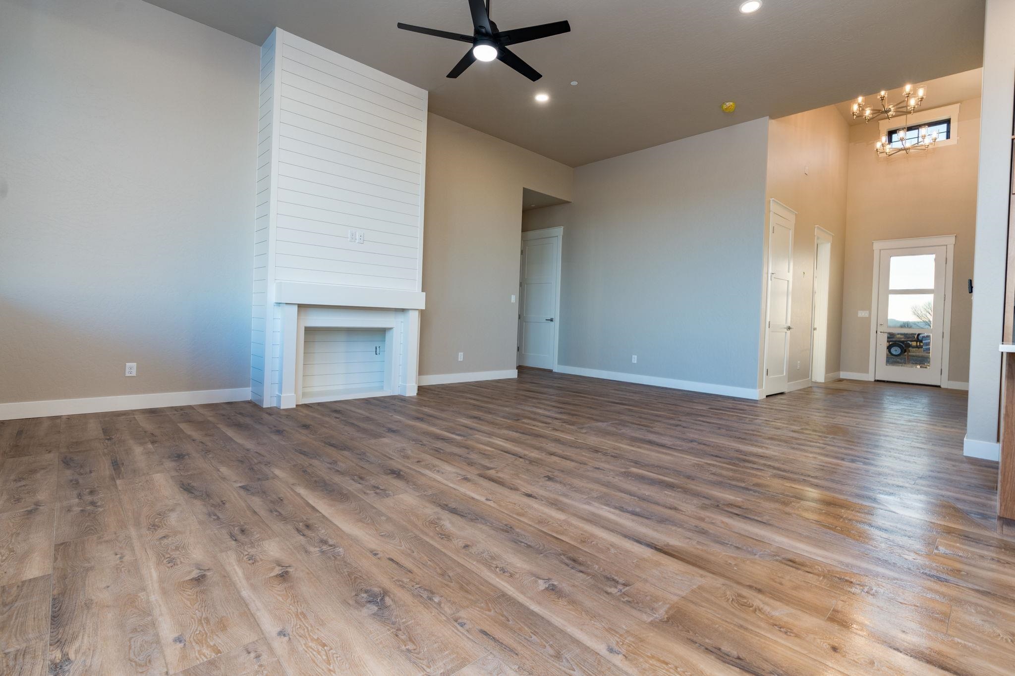 1928 K Road Fruita, CO 81521 - Photo 21 of 32 an empty room with wooden floor a ceiling fan and kitchen view