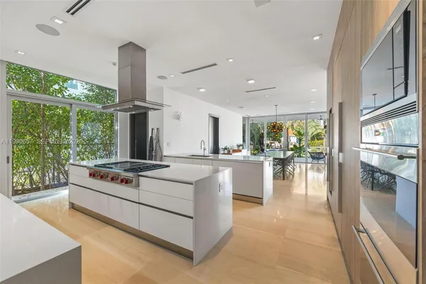 a kitchen with granite countertop a refrigerator a sink and white cabinets