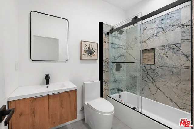 a bathroom with a bathtub shower sink mirror and toilet