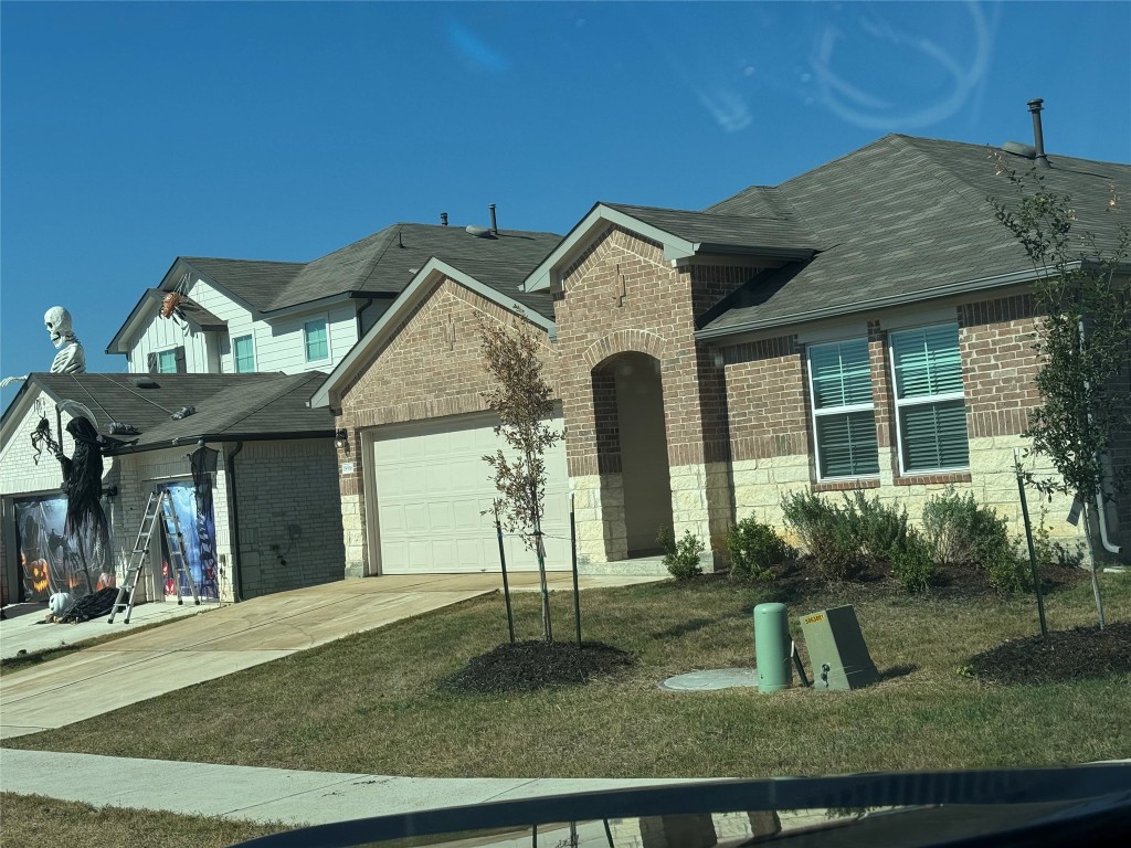 19516 Ann Richards Avenue Manor, TX 78653 - Photo 2 of 35 View of front facade with concrete driveway, brick siding, a garage, and a front lawn