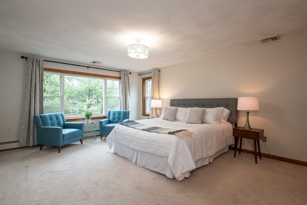 159 Willow Street Acton, MA 01720 - Photo 4 of 34 a bedroom with a bed and a couch with exposed radiator