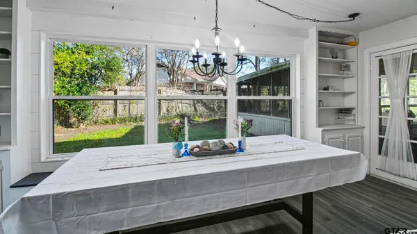 a view of a dining room with furniture a chandelier and large windows