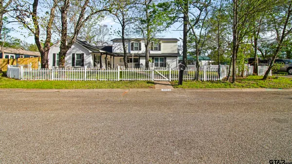 a view of house with a yard and large trees