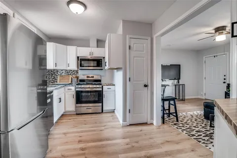 a kitchen with granite countertop a refrigerator and a stove top oven