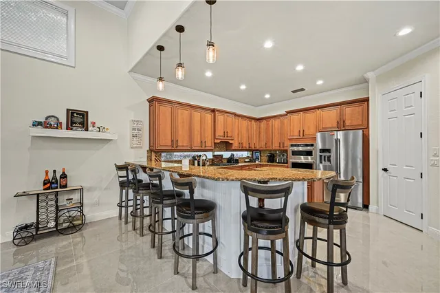 a kitchen with stainless steel appliances kitchen island granite countertop a table chairs sink and cabinets