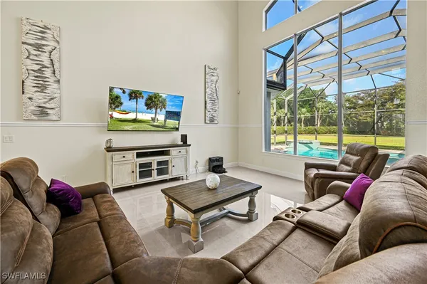 a living room with furniture a flat screen tv and a floor to ceiling window