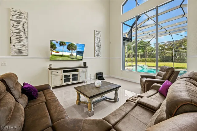 a living room with furniture a flat screen tv and a floor to ceiling window
