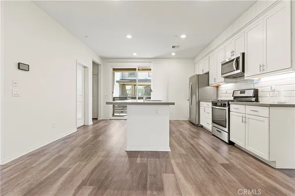 a kitchen with granite countertop a refrigerator and a stove top oven