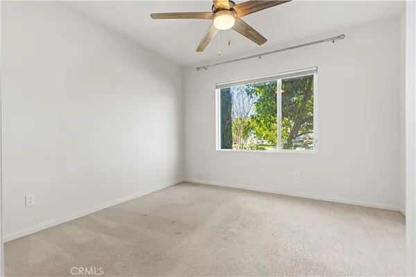 an empty room with a window and a fan