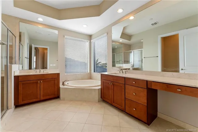 a spacious bathroom with a granite countertop double vanity sink a mirror and a bathtub