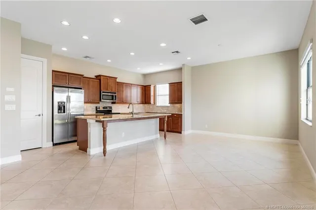 a large kitchen with kitchen island a sink a stove a center island and a window