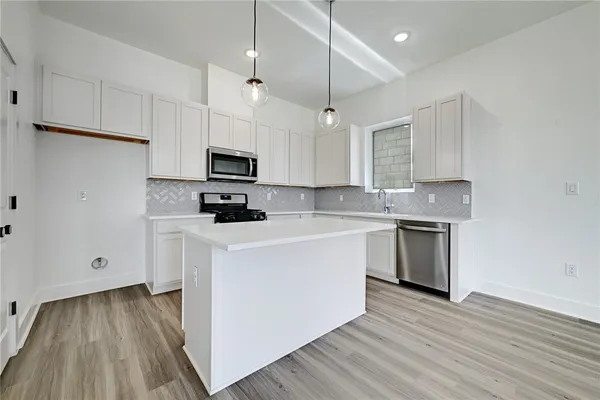 a kitchen with stainless steel appliances granite countertop a stove a sink and a microwave