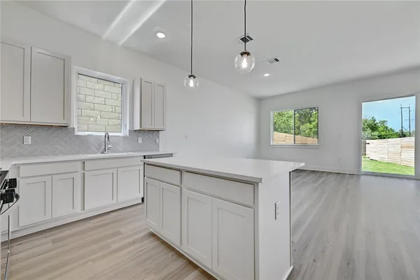 a kitchen with white cabinets and window