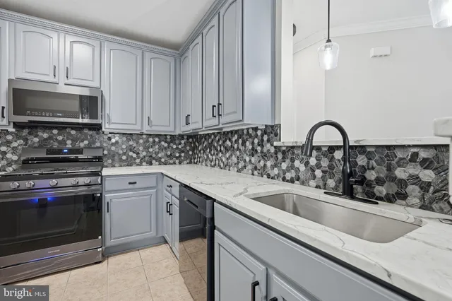 a kitchen with stainless steel appliances white cabinets and a stove a refrigerator with grey appliances