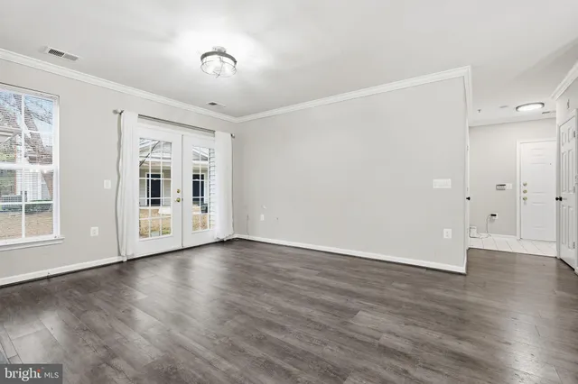 an empty room with wooden floor fireplace and windows