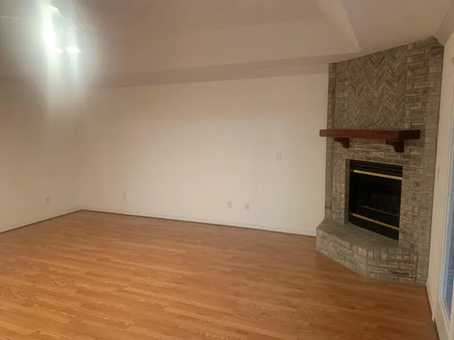 a view of an empty room with wooden floor and a fireplace