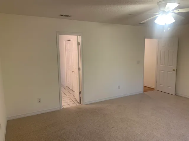 an empty room with a ceiling fan and closet area