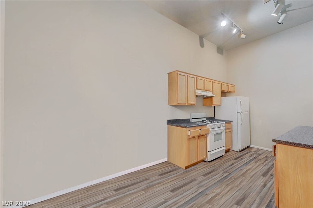 2305 West Horizon Ridge Parkway, Unit 1223 Henderson, NV 89052 - Photo 10 of 28 Kitchen featuring dark countertops, light wood finish cabinets, white gas stove, rail lighting, and light wood-style floors