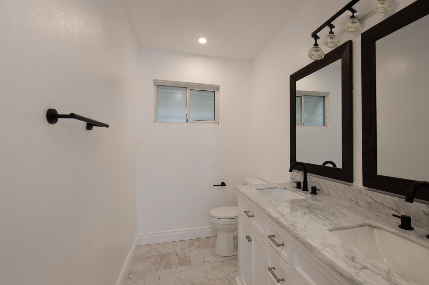 5167 East Dwight Way Fresno, CA 93727 - Photo 11 of 30 a bathroom with a sink a toilet and a mirror