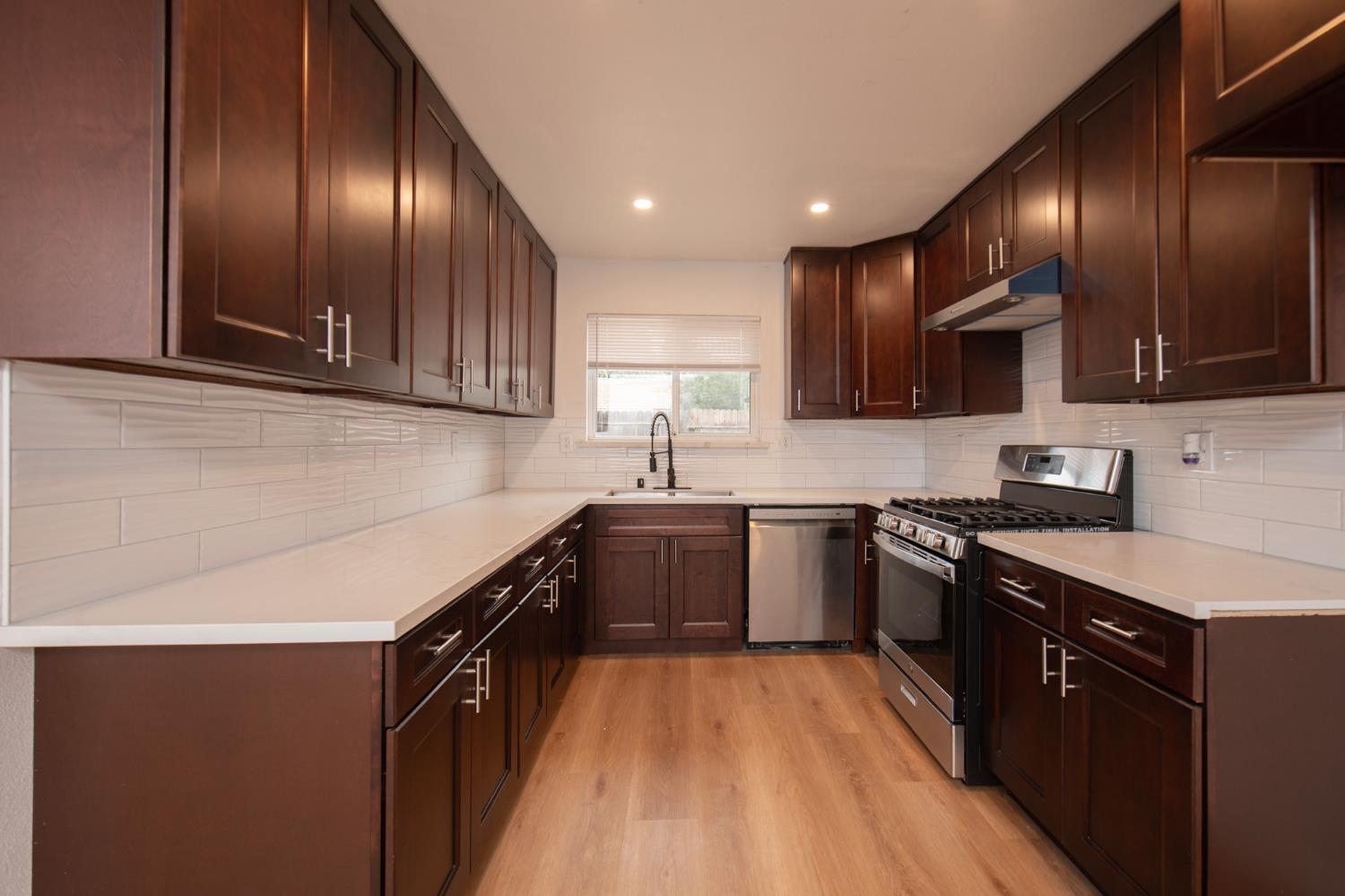 5167 East Dwight Way Fresno, CA 93727 - Photo 4 of 30 a kitchen with stainless steel appliances granite countertop wooden cabinets a stove top oven a sink and dishwasher