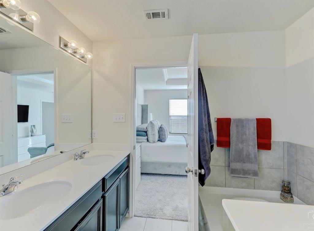 2207 Heaton Street Forney, TX 75126 - Photo 16 of 25 Bathroom vanity featuring dual sinks with chrome fixtures, a long mirror, and contemporary light bar