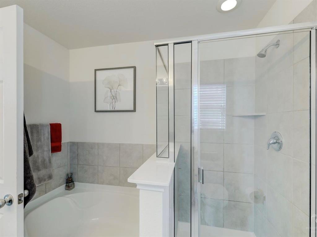 2207 Heaton Street Forney, TX 75126 - Photo 17 of 25 Bathroom featuring a built-in corner soaking tub and an enclosed shower with a glass door, tiled walls, and a recessed shelf