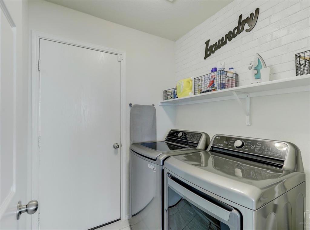 2207 Heaton Street Forney, TX 75126 - Photo 23 of 25 Dedicated laundry area featuring white walls, open shelving, and a decorative textured accent wall