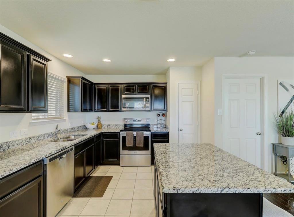 2207 Heaton Street Forney, TX 75126 - Photo 8 of 25 Kitchen featuring a large island with a light-toned countertop, dark cabinetry, stainless steel appliances, and recessed lighting
