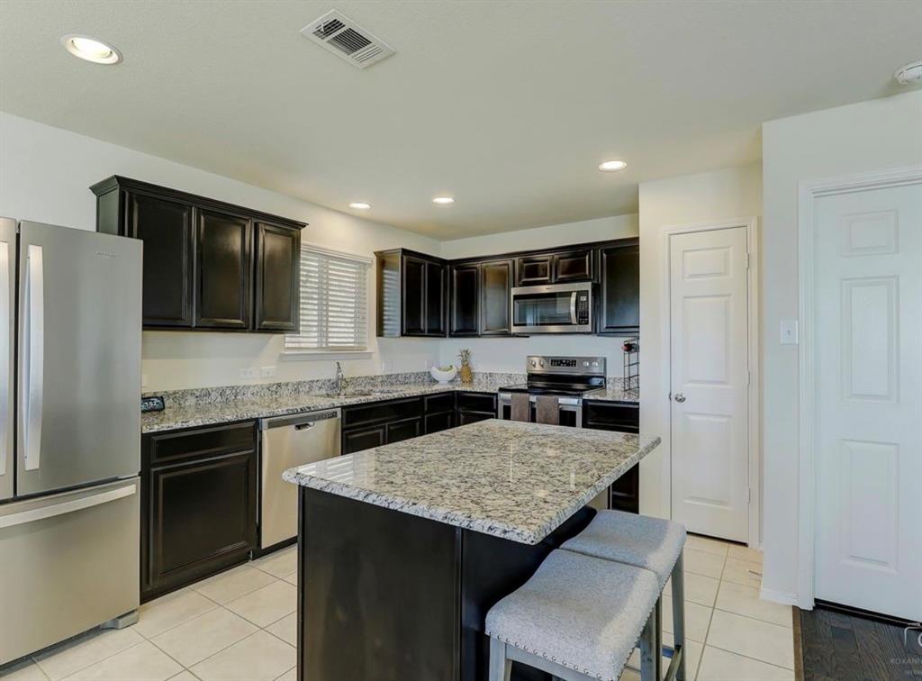 2207 Heaton Street Forney, TX 75126 - Photo 9 of 25 Kitchen featuring dark wood cabinetry, light-colored granite countertops, and stainless steel appliances