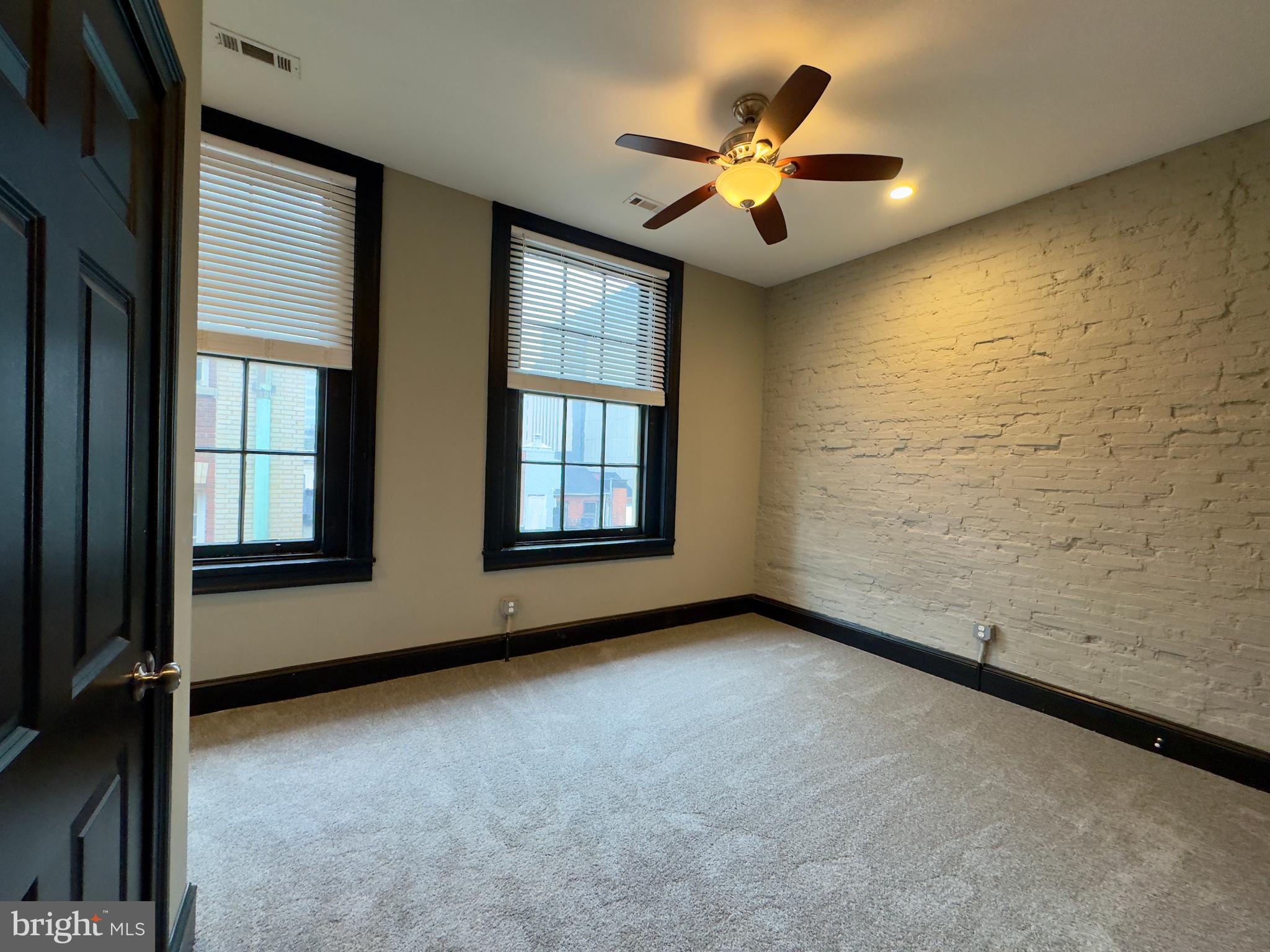 7 West Mulberry Street, Unit 8 Baltimore, MD 21201 - Photo 7 of 18 an empty room with windows and ceiling fan