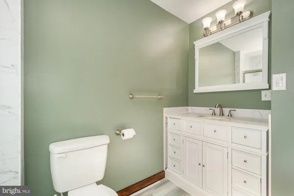a bathroom with a granite countertop toilet sink and mirror