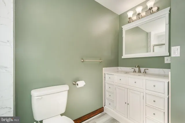 a bathroom with a granite countertop toilet sink and mirror