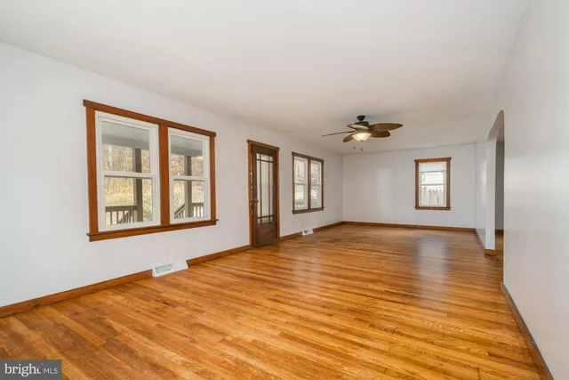 a view of an empty room with wooden floor and a window