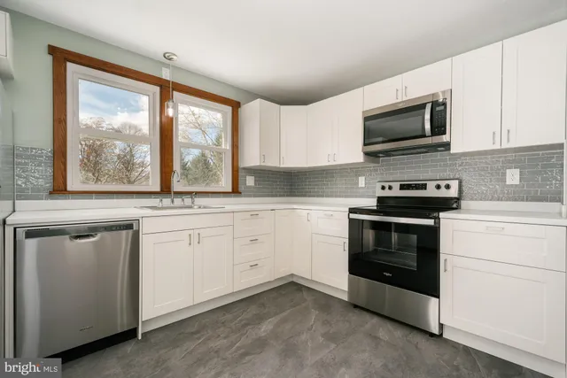 a kitchen with white cabinets appliances and a window