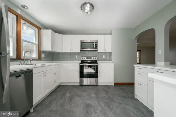 a kitchen with granite countertop a refrigerator stove and sink