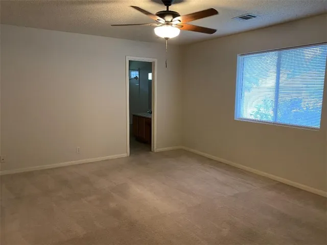 an empty room with windows and fan