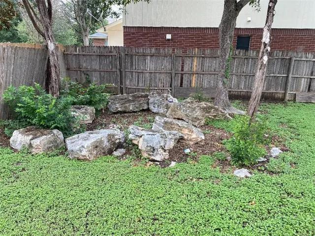 a view of a backyard with plants and wooden fence