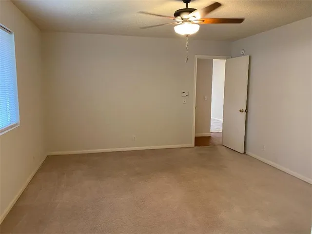 an empty room with a chandelier fan and windows