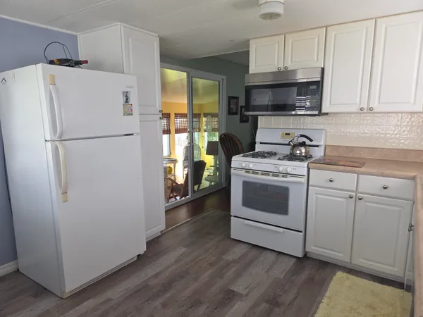 a white refrigerator freezer sitting inside of a kitchen with stainless steel appliances granite countertop a refrigerator stove a sink and dishwasher with wooden floor