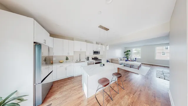 a large white kitchen with cabinets a stove a sink and a dining table with wooden floor