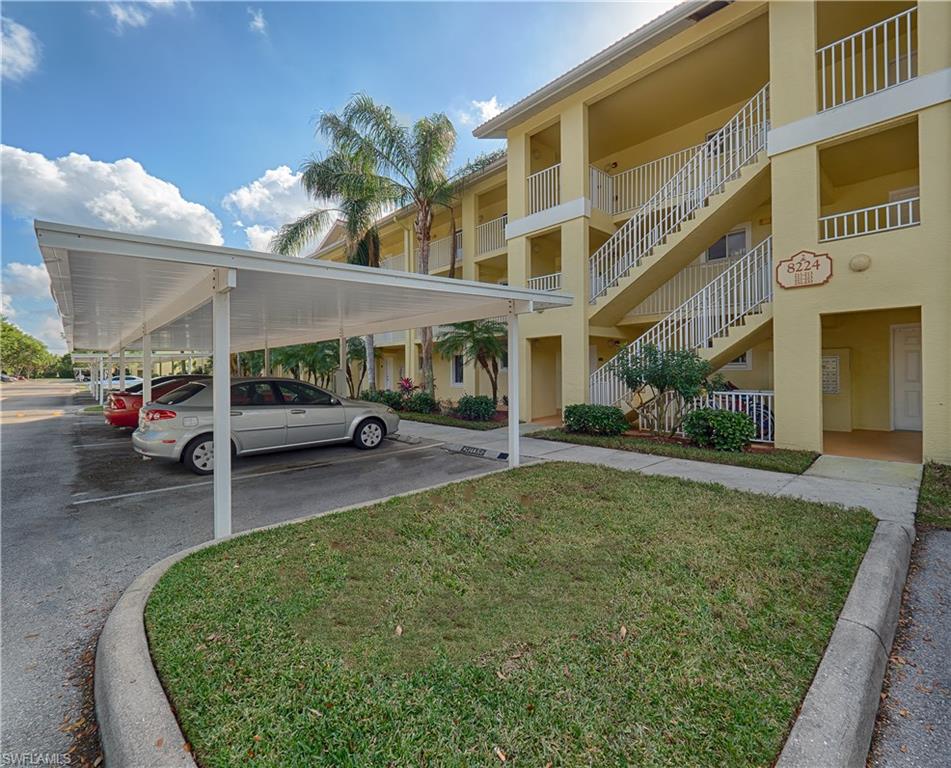 8224 Key Royal Circle, Unit 223 Naples, FL 34119 - Photo 13 of 14 a front view of a building with a garden and car parked