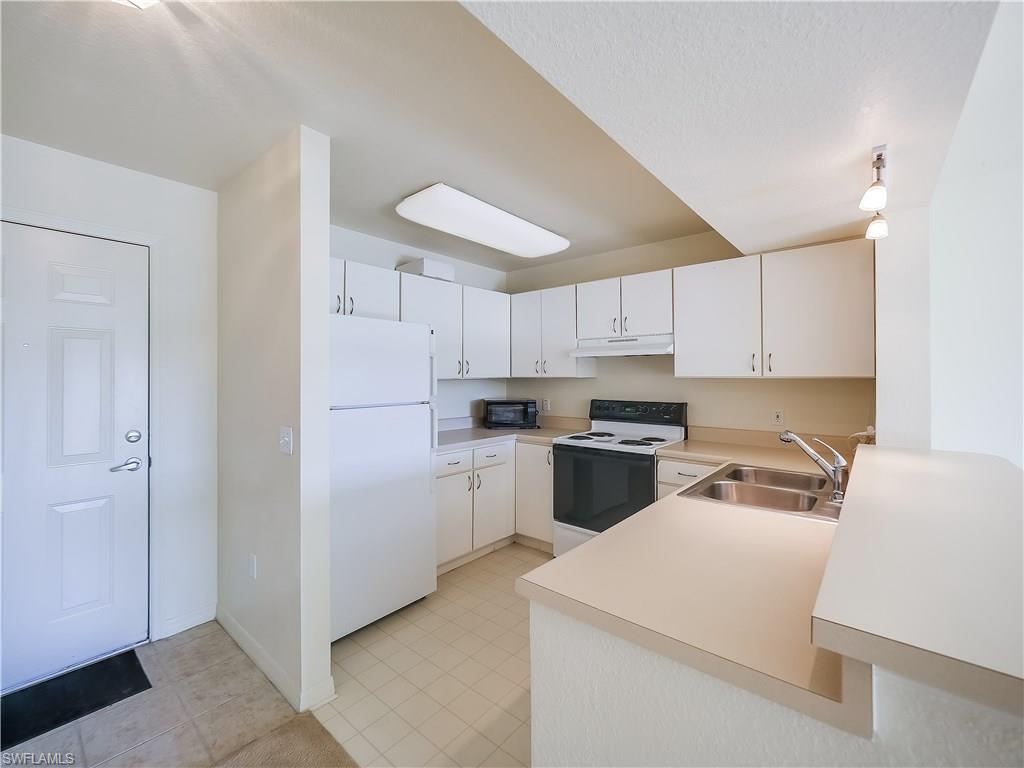 8224 Key Royal Circle, Unit 223 Naples, FL 34119 - Photo 6 of 14 a kitchen with a refrigerator a stove top oven a sink and cabinets