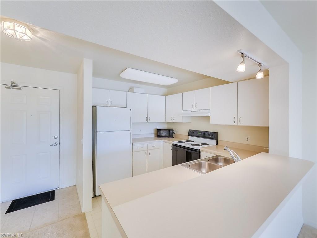 8224 Key Royal Circle, Unit 223 Naples, FL 34119 - Photo 8 of 14 a kitchen with a refrigerator a stove top oven a sink and cabinets