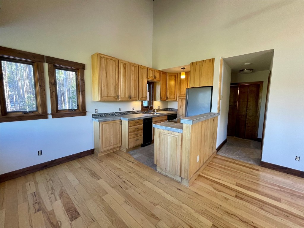 204 Blue Ridge Road Breckenridge, CO 80424 - Photo 8 of 40 Kitchen featuring sink, a towering ceiling, stainless steel refrigerator, and light hardwood / wood-style flooring