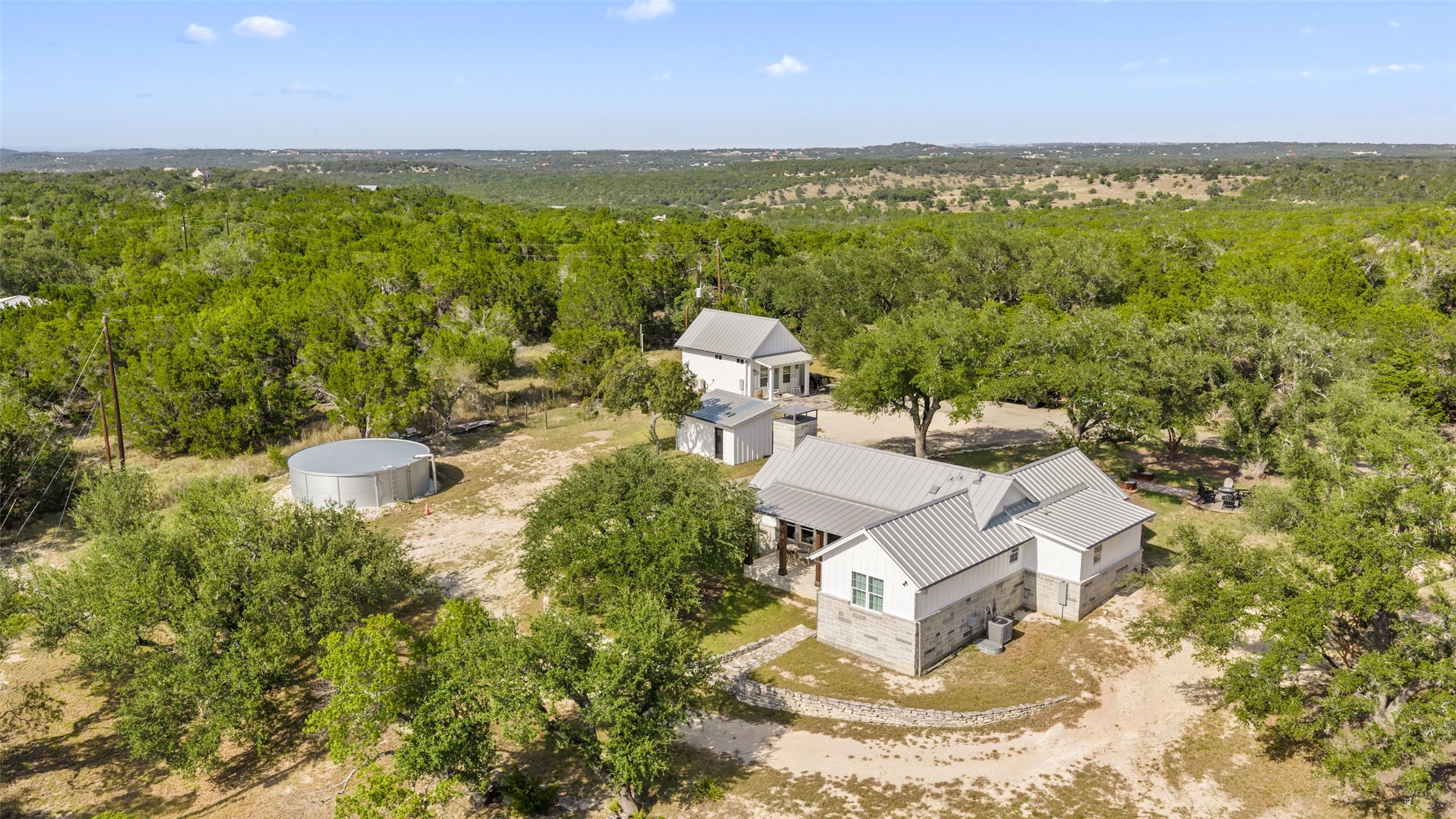 810 Kothmann Road Dripping Springs, TX 78620 - Photo 2 of 40 An aerial perspective showcases a secluded estate nestled among mature trees and rolling hills.